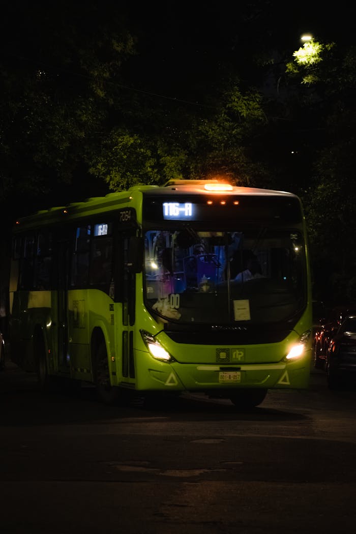 services-bg A bright green city bus navigating a street at night under urban lighting.
