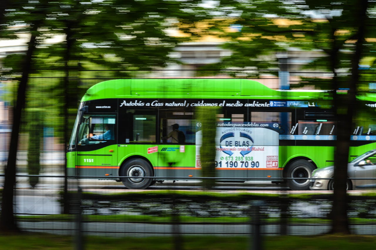 services-03 A green natural gas bus in motion on a city street, emphasizing eco-friendly transportation.